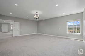 Empty room featuring carpet flooring, recessed lighting, and a chandelier