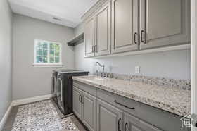 Washroom with cabinet space, washer and clothes dryer, and light tile patterned floors