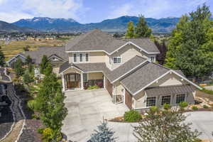 View of front of house with composition shingle roof, concrete driveway, stone  and wood siding, mountain view, 3 -car garage