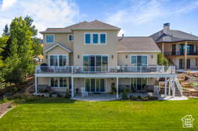 Rear view of house with a patio, a lawn, stairway, and a deck