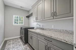 Upstairs Laundry area with light tile patterned floors, cabinet space, washer and clothes dryer