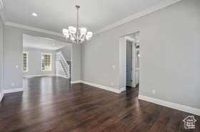 Unfurnished living room featuring ornamental molding, a chandelier, dark wood-style flooring, stairway, and recessed lighting