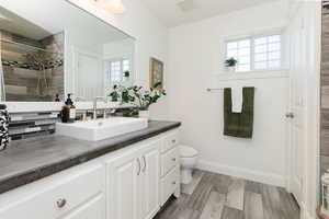 Bathroom with vanity, light wood finished floors, tiled shower, and backsplash