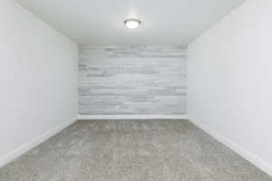 Carpeted spare room with baseboards and an accent wall