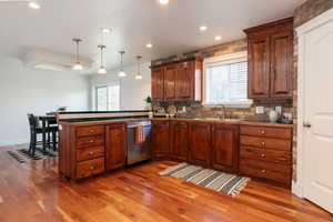 Kitchen with backsplash, hanging light fixtures, recessed lighting, a peninsula, and dark wood-style floors