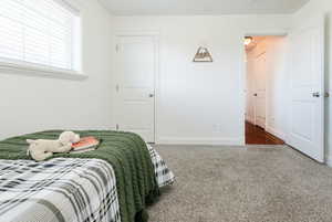Bedroom with dark colored carpet and baseboards