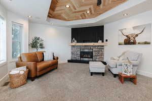 Living area featuring a raised ceiling, recessed lighting, a fireplace, and carpet floors