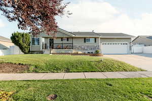 Single story home with driveway, a garage, and stone siding