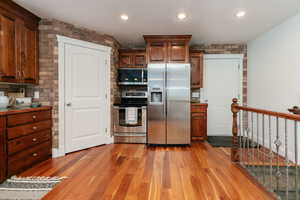 Kitchen featuring stainless steel appliances, light wood-type flooring, recessed lighting, brown cabinetry, and backsplash