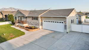 Ranch-style house featuring stone siding, driveway, a shingled roof, a mountain view, and a garage
