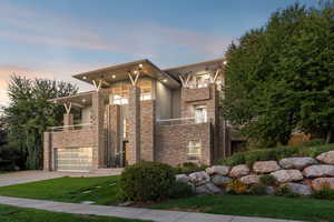 Contemporary home with a balcony, concrete driveway, stone siding, stucco siding, and an attached garage