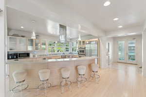 Kitchen featuring glass insert cabinets, Bamboo cabinets, a kitchen bar, and Quartz countertops