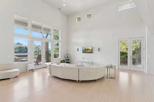 Living room with french doors, a towering ceiling, Bamboo floors, and recessed lighting