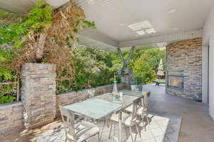View of patio featuring outdoor dining area and an outdoor stone fireplace