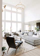 Living area featuring a chandelier, light wood-style floors, recessed lighting, and a towering ceiling