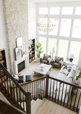 Living room featuring a glass covered fireplace, light wood-style floors, a chandelier, and a high ceiling