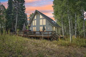 Back of house with a deck and a shingled roof
