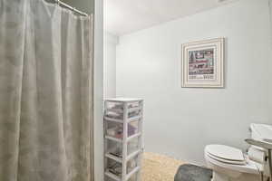 Bathroom with toilet and curtained shower