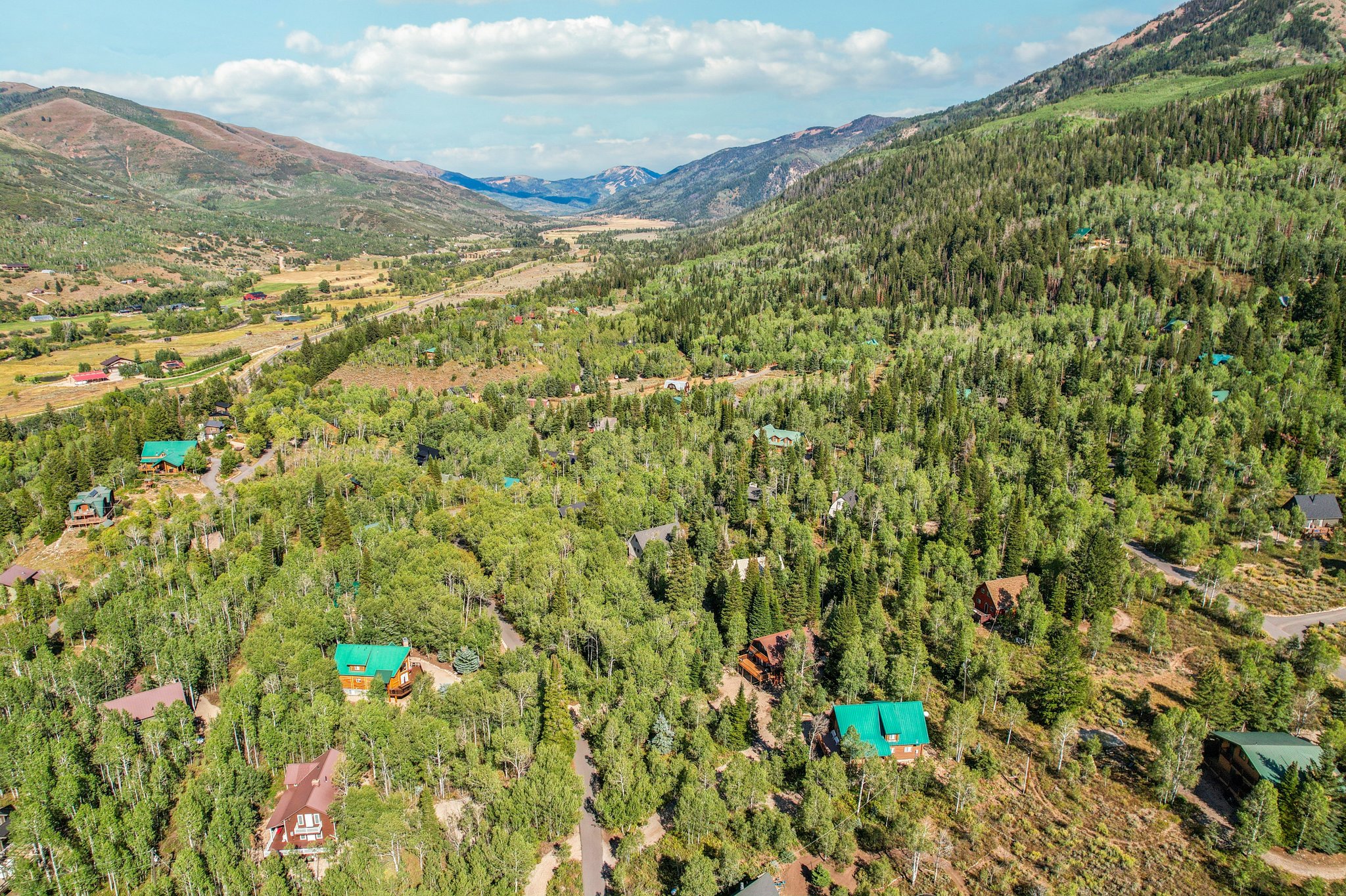 Aerial view of property and surrounding area featuring a mountain backdrop and a forest
