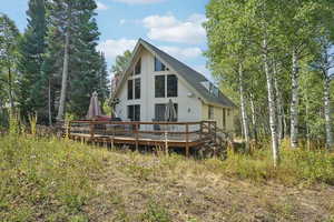 Back of house featuring a deck, a shingled roof, and a chimney