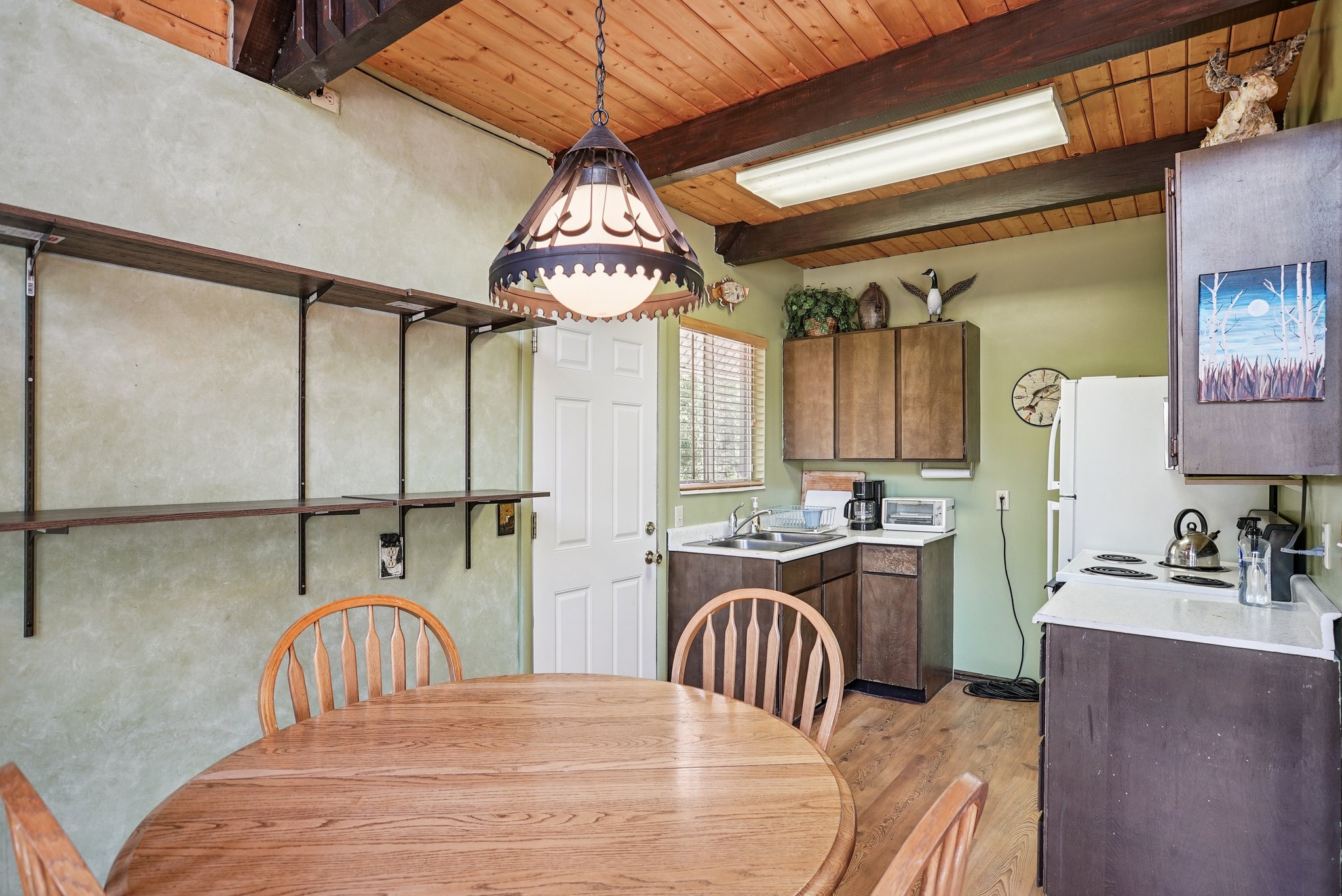 Dining room featuring light wood-style flooring and a wood ceiling with exposed beams