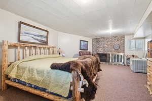 Carpeted bedroom with a brick fireplace