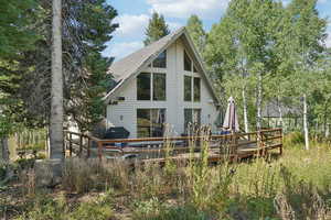 Back of property featuring a deck and a shingled roof