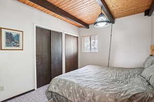 Carpeted bedroom featuring two closets and wooden ceiling