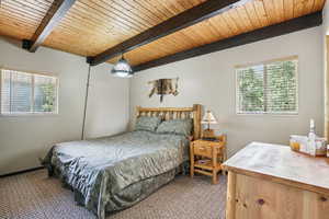 Bedroom with carpet flooring and a wooden ceiling with exposed beams