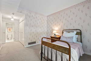 Bedroom featuring wallpapered walls, carpet, and connected bathroom