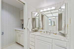 Full bath featuring vanity, wallpapered walls, and light tile patterned floors