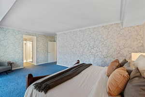 Bedroom with crown molding, wallpapered walls, and carpet