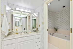 Bathroom featuring a garden tub, vanity, and light tile patterned flooring