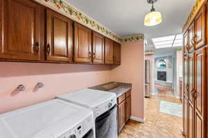 Laundry area featuring a large fireplace, washer and dryer, and cabinet space