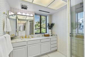 Full bathroom featuring wallpapered walls, vanity, a stall shower, and light tile patterned floors