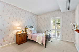 Bedroom with wallpapered walls and light colored carpet