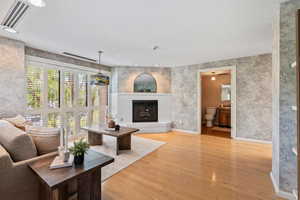 Living area with wallpapered walls, light wood-style flooring, a brick fireplace, and recessed lighting