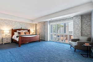 Bedroom with wallpapered walls, carpet flooring, ornamental molding, and access to outside