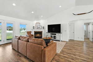 Living room featuring arched walkways, lofted ceiling, recessed lighting, fireplace, and wood finished floors