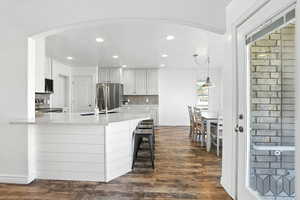 Kitchen with appliances with stainless steel finishes, an open bar, light quartz counters