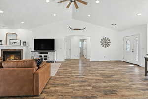 Living area featuring vaulted ceiling, arched walkways, ceiling fan, a fireplace, and recessed lighting