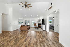Living area with arched walkways, high vaulted ceiling, ceiling fan, healthy amount of natural light, and  fireplace