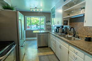 Kitchen featuring backsplash, open shelves, dishwasher, white cabinets,