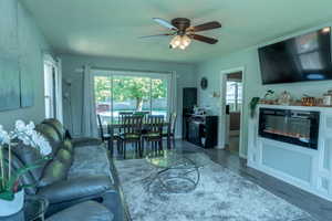 Living room featuring laminate finished floors, a glass covered fireplace, and ceiling fan