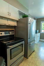 Kitchen with appliances with stainless steel finishes, white cabinets,