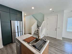 Kitchen with stainless steel appliances, a textured ceiling, dark wood-style flooring, recessed lighting, and a center island