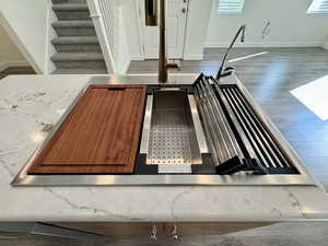 Kitchen view of wood finished floors, light stone countertops, and brown cabinetry