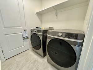 Washroom with tile patterned flooring and washer and clothes dryer