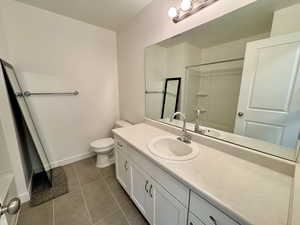 Full bathroom with dark tile patterned floors, vanity, and shower / tub combo