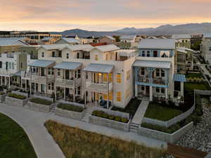 Back of property at dusk featuring a residential view, a mountain view, a metal roof, and stucco siding